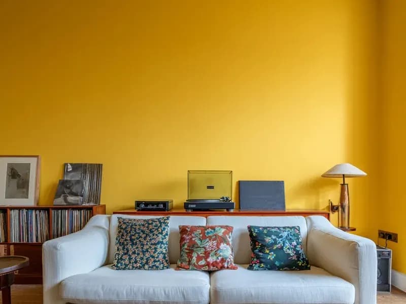 An ochre yellow living room wall above a sofa