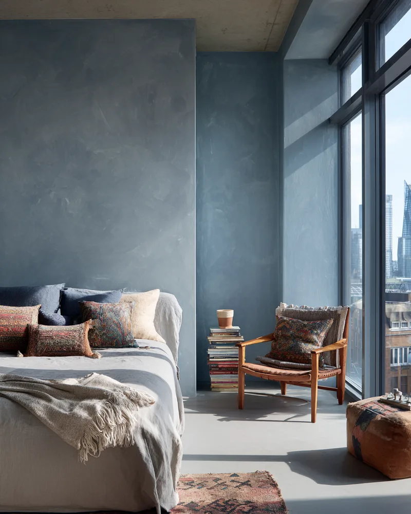 Warehouse bedroom with blue-grey walls and city view